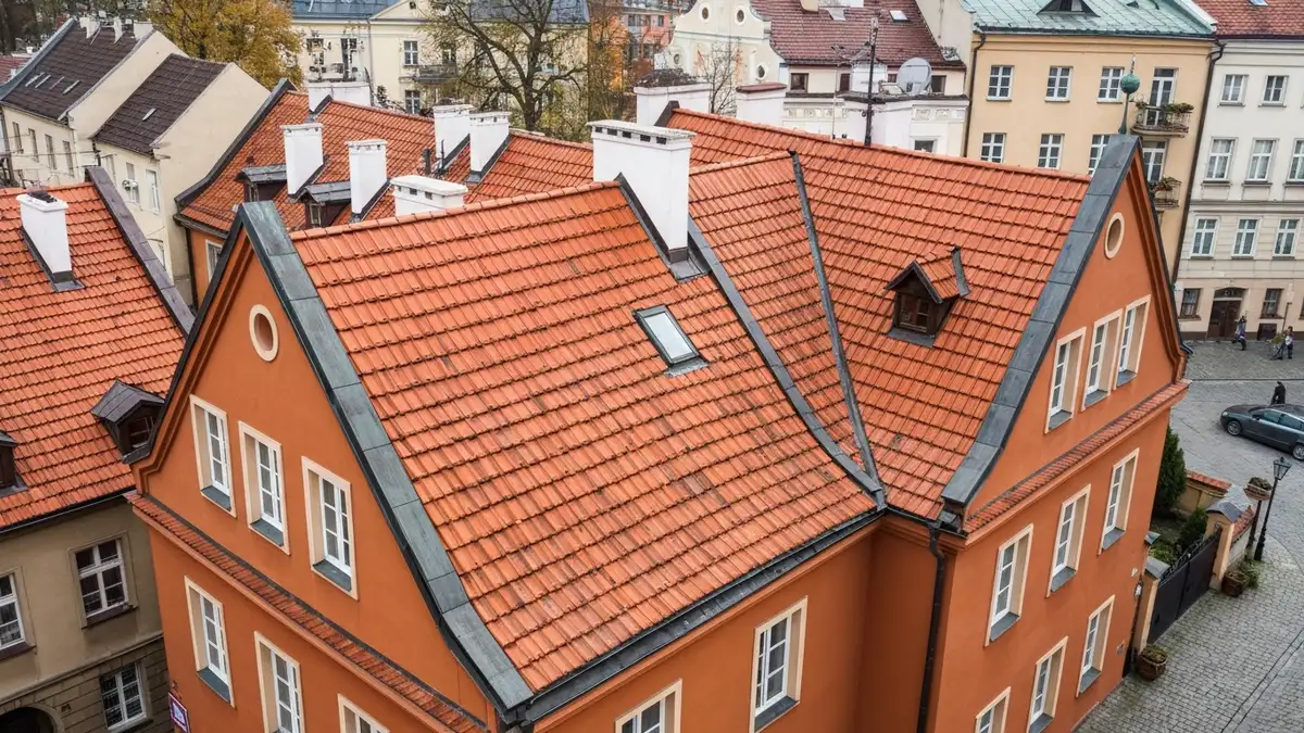 Dach zabytkowej kamienicy pokryty dachówką ceramiczną karpiówką w centrum polskiego miasta